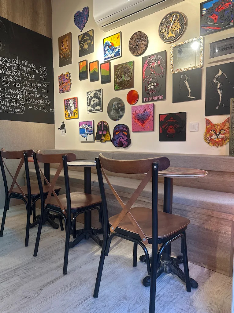 Kahve menüsünün yazılı olduğu kara tahta ve sanat eserleriyle dolu oturma alanı